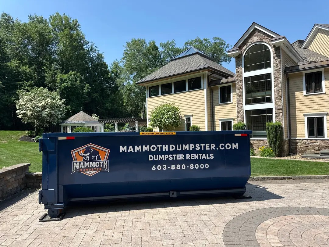 Mammoth roll off dumpster on driveway protection mats on a paver driveway